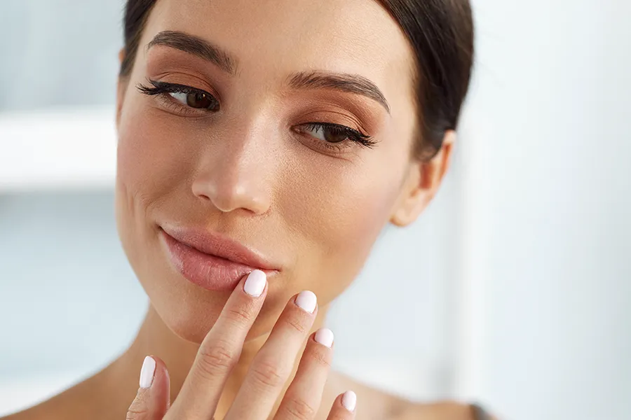 A beautiful brunette touches her faces. Get aesthetic dermal fillers from Don D. Fisher, D.O. at The BEST Program in Fort Lauderdale.