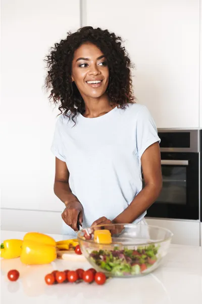 A smiling black woman prepares a healthy salad. Get BPC-157 Peptide Therapy from Don D. Fisher, D.O. at The BEST Program in Fort Lauderdale.