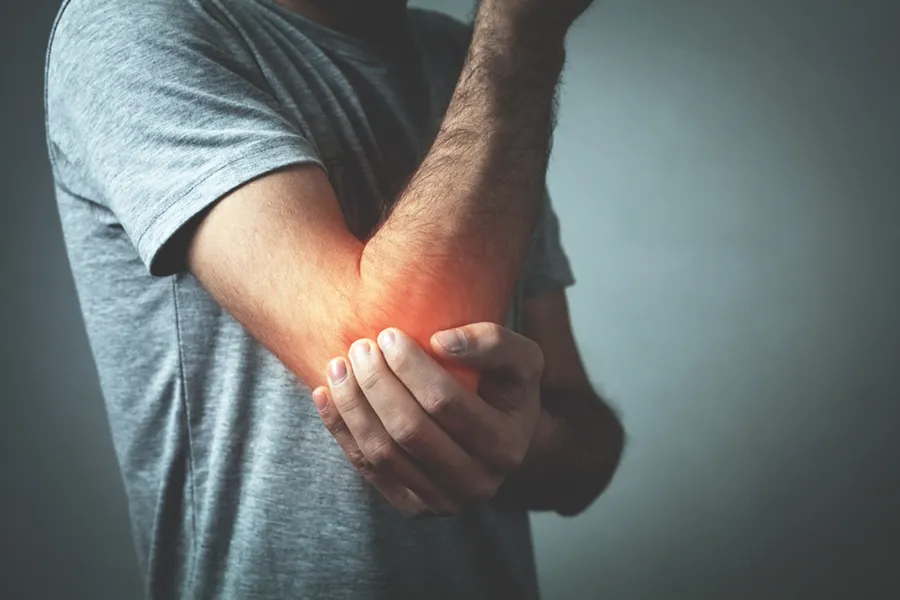 A man holds his elbow, glowing with pain. Get biologic allograft treatment from Don D. Fisher, D.O. at The BEST Program in Fort Lauderdale.