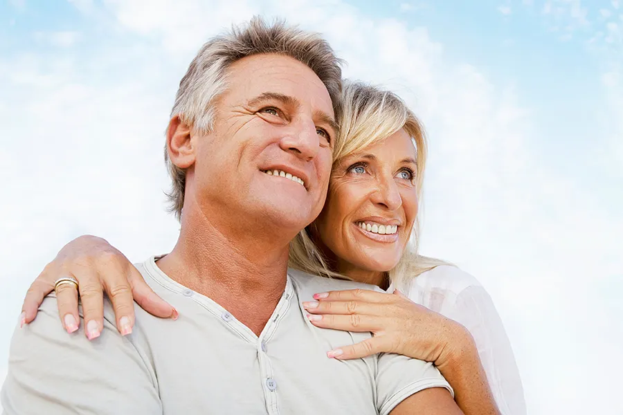 A mature couple embraces outside under the sky. Get CJC 1295 with Ipamorelin anti-aging peptide therapy from Don D. Fisher, D.O. at The BEST Program in Fort Lauderdale.