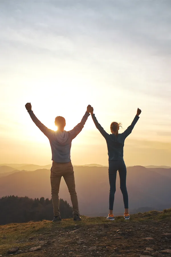 A couple raises their hands in triumph on a mountaintop. Get DHEA hormone therapy from Don D. Fisher, D.O. at The BEST Program in Fort Lauderdale.