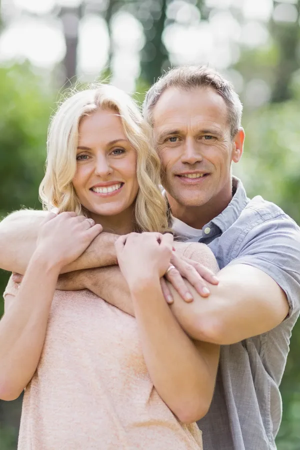 A middle-aged couple embrace outdoors on a sunny day. Get HGH hormone therapy from Don D. Fisher, D.O. at The BEST Program in Fort Lauderdale.