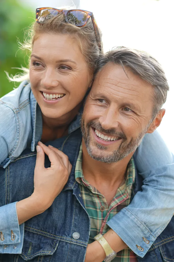 A couple in denim jackets embrace playfully outdoors. Get hypogonadism treatment from Don D. Fisher, D.O. at The BEST Program in Fort Lauderdale.