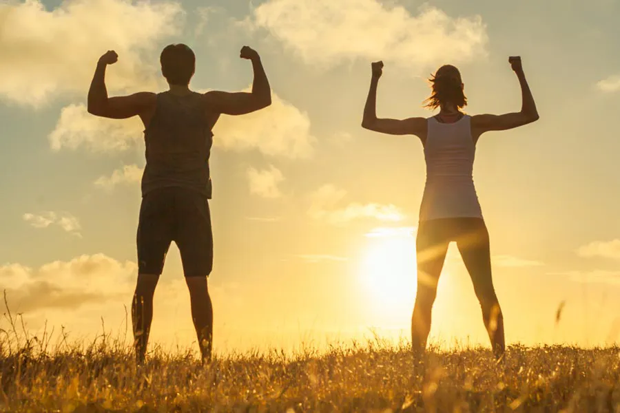 A couple raise their arms triumphantly, silhouetted by the sunrise. Schedule Immune Boost injections from Don D. Fisher, D.O. at The BEST Program in Fort Lauderdale.
