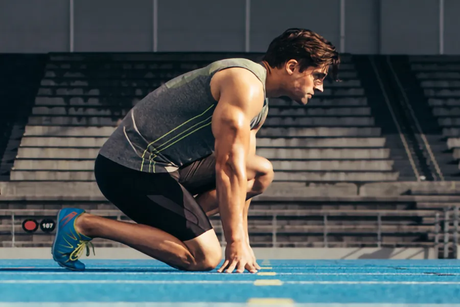 A white man kneels at the starting line on a track, determined to do his best. Get treatment for lean muscle loss and recovery from Don D. Fisher, D.O. at The BEST Program in Fort Lauderdale.