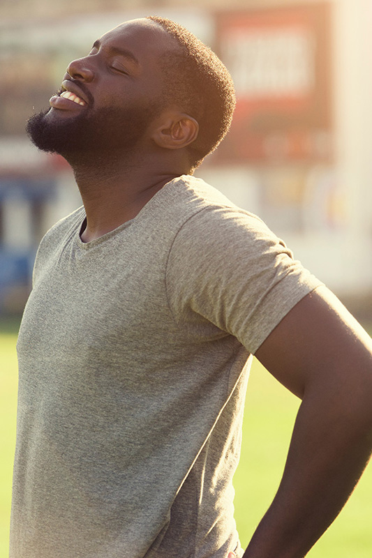 A black man in a gray t-shirt and smiles, looking up with closed eyes after a satisfying workout. Get treatment for lean muscle loss and recovery from Don D. Fisher, D.O. at The BEST Program in Fort Lauderdale.