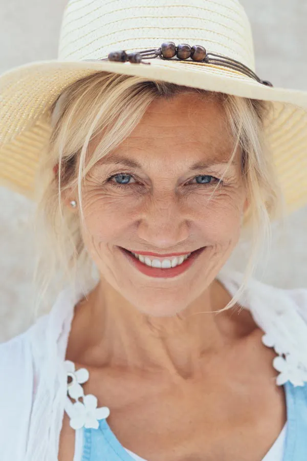 A beautiful, smiling older woman with blonde hair and a sunhat, happy with menopause treatment from Don D. Fisher, D.O. at The BEST Program in Fort Lauderdale.