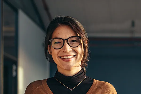 A brunette woman with glasses smiles in a gray-blue walled office. Get metabolic syndrome from Don D. Fisher, D.O. at The BEST Program in Fort Lauderdale.