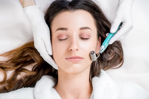 A woman in a white robe closes her eyes and receives a microneedling procedure from Don D. Fisher, D.O. at The BEST Program in Fort Lauderdale.