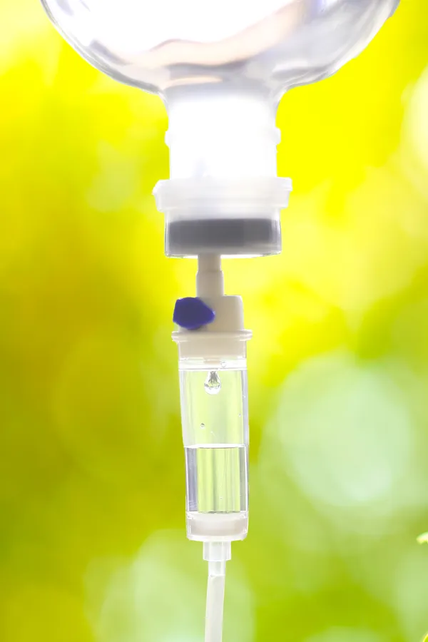 Close up of an IV drip with a lush, green background. Get NAD Therapy from Don D. Fisher, D.O. at The BEST Program in Fort Lauderdale.