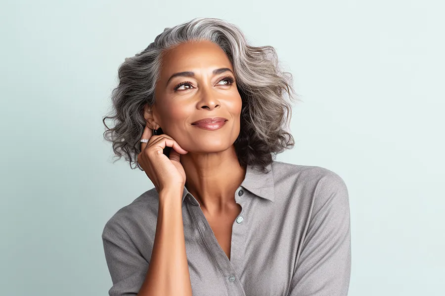 An older African-American woman in a gray blouse looks up and smiles, happy with the beautiful results of her PDO thread facelift treatment from Don D. Fisher, D.O. at The BEST Program in Fort Lauderdale.