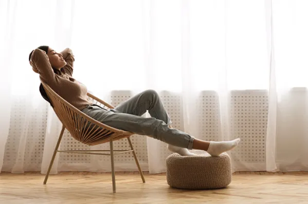 A woman takes a nap in a chair by the window. Schedule the Rest and Restore peptide blend from Don D. Fisher, D.O. at The BEST Program in Fort Lauderdale.