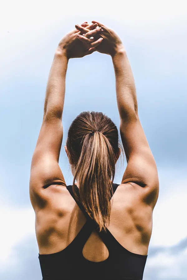 A toned woman stretches post-workout. Get the Rest and Restore peptide blend from Don D. Fisher, D.O. at The BEST Program in Fort Lauderdale.