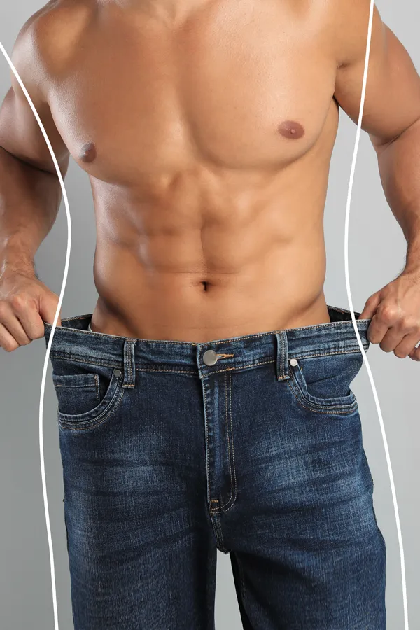 A strong shirtless man in jeans holds the waistlines of his too-big jeans to show the success of semaglutide weight loss from Don D. Fisher, D.O. at The BEST Program in Fort Lauderdale.