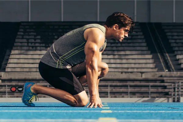 With a determined look, Aamuscular man in track clothes kneels at the start of a race. Get Sermorelin peptide therapy from Don D. Fisher, D.O. at The BEST Program in Fort Lauderdale.