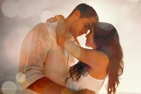 A couple in linen shirts standing in a sparkling light embraces each other with their foreheads touching and eyes closed, happy with their sexual wellness treatments from Don D. Fisher, D.O. at The BEST Program in Fort Lauderdale.