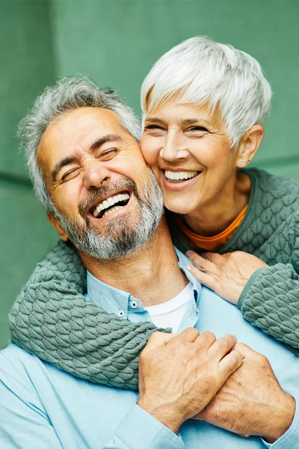A slim mature couple embrace on their porch. Get Super Slim Shot for weight loss from Don D. Fisher, D.O. at The BEST Program in Fort Lauderdale.