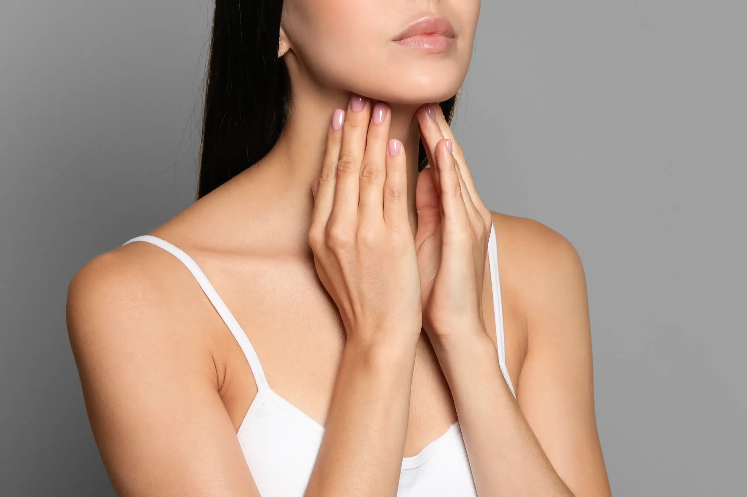 A woman in a white tank top touches her neck looking for signs of thyroid disorder. Get help for thyroid disorders from Don D. Fisher, D.O. at The BEST Program in Fort Lauderdale.